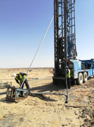 Technician working at the base of a drill rig during well construction